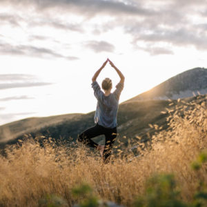 Junge Frau macht Yoga in den Bergen im Morgenlichz